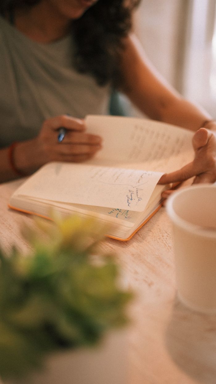 Mastering the First Impression: Your intriguing post title goes here Close-up of a person writing in a notebook with a coffee cup nearby, warm setting.
