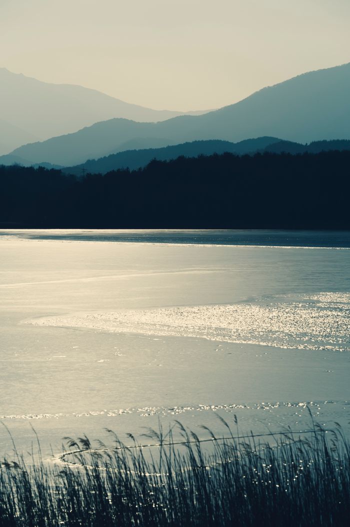 Beautiful twilight scene of a lake with mountains silhouetted in the background, exuding tranquility.
